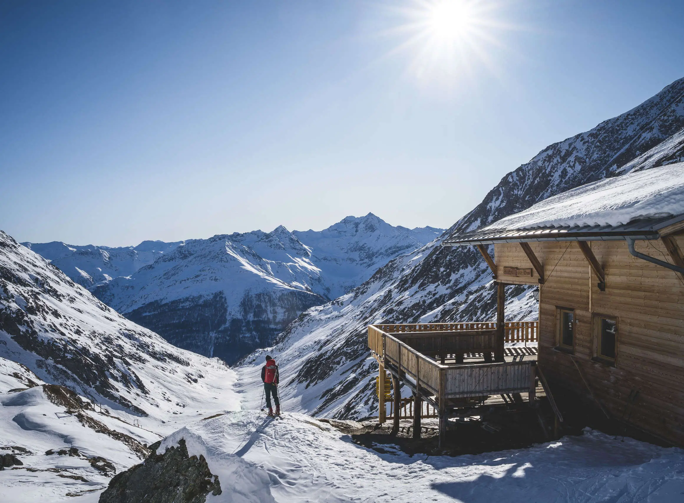 Cross-country skier near a wooden hut with panoramic snowy peaks in the Dolomites Sillian.